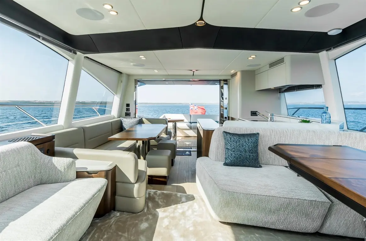 Luxurious yacht interior featuring a spacious lounge, dining area, and panoramic sea views through large windows.